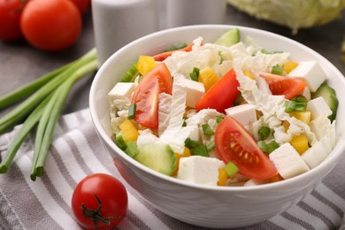 Photo of Tasty salad with Chinese cabbage, cheese, pepper, tomato and green onion on table, closeup