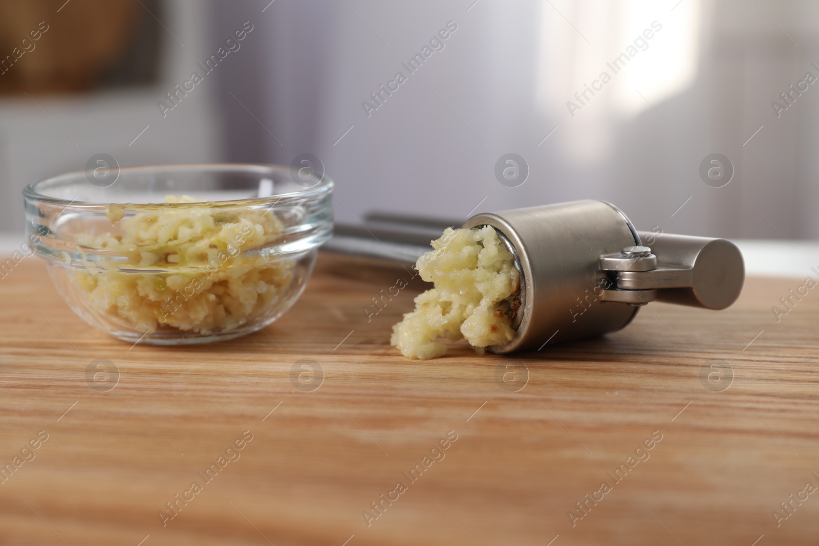 Photo of Garlic press and mince on wooden table indoors, closeup