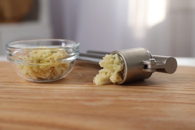 Photo of Garlic press and mince on wooden table indoors, closeup