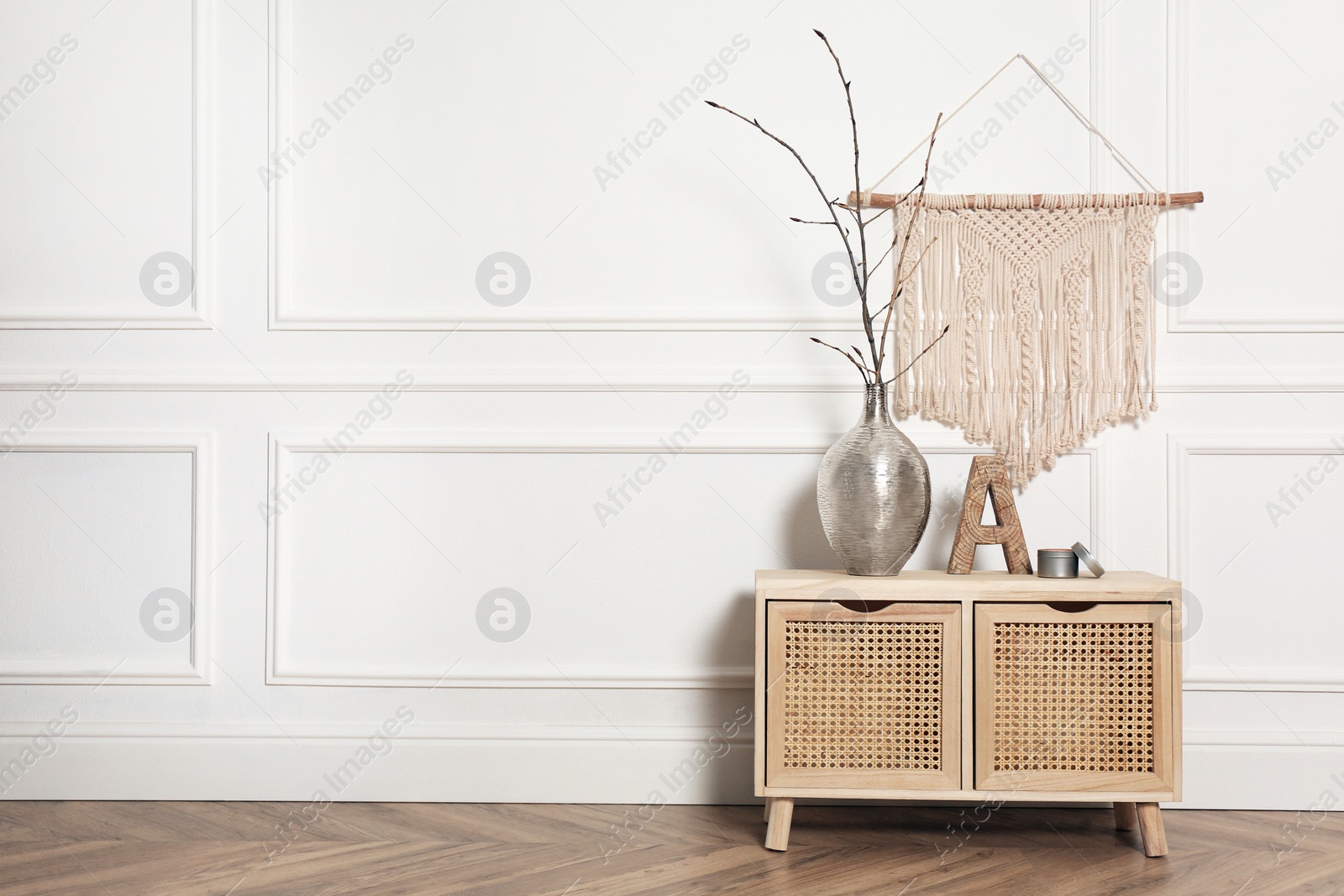 Photo of Tree twigs and decor on wooden table near white wall in room. Space for text