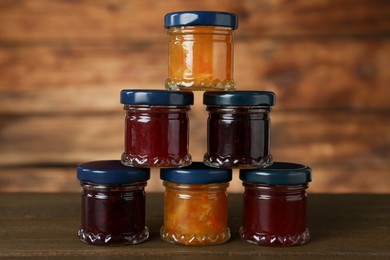 Photo of Jars of different jams on wooden table