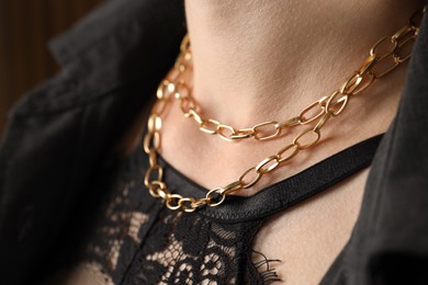 Photo of Woman wearing stylish metal chain, closeup. Luxury jewelry