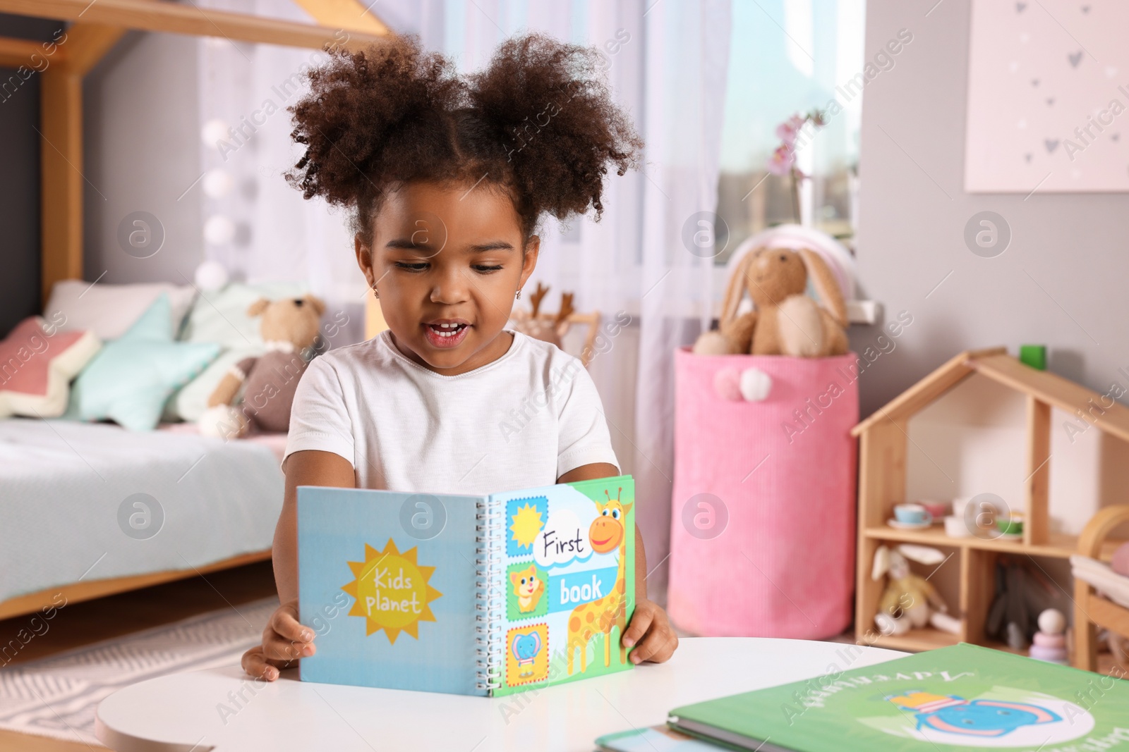 Photo of African American girl reading book at home