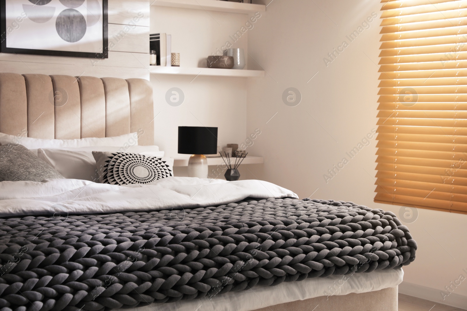 Photo of Soft chunky knit blanket on bed in stylish room interior