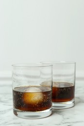 Photo of Cocktails with ice balls on white marble table, space for text