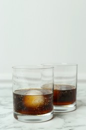 Cocktails with ice balls on white marble table, space for text