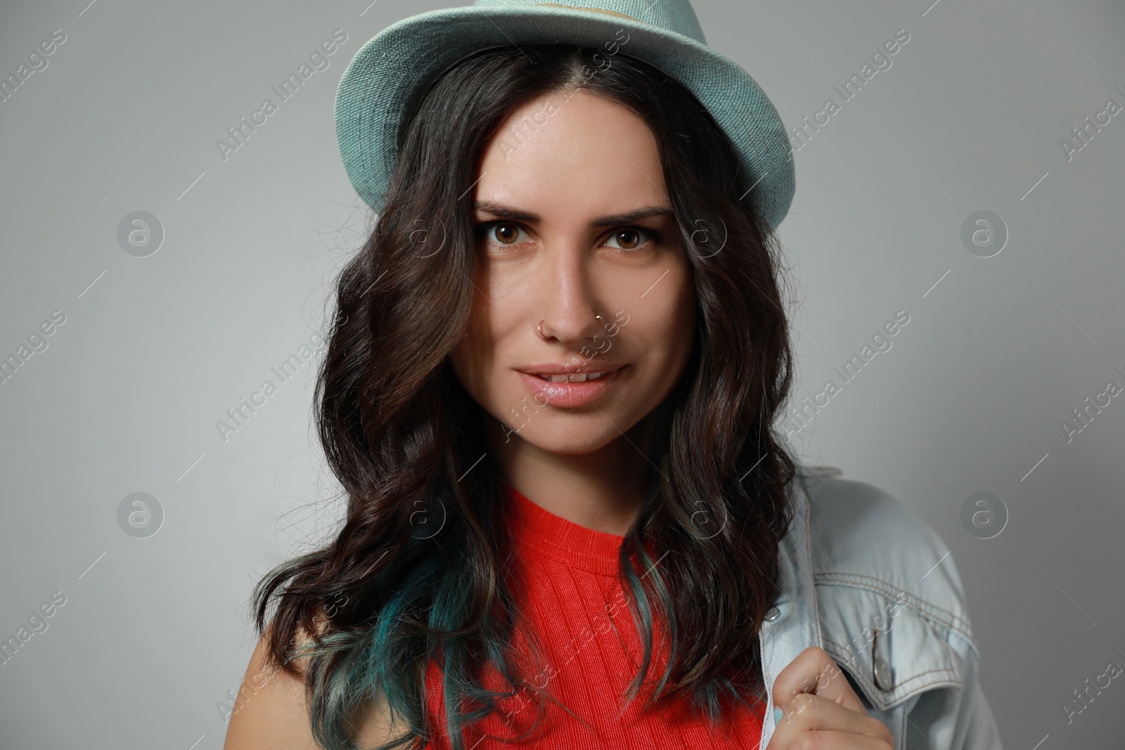 Photo of Beautiful young woman with nose piercing on grey background