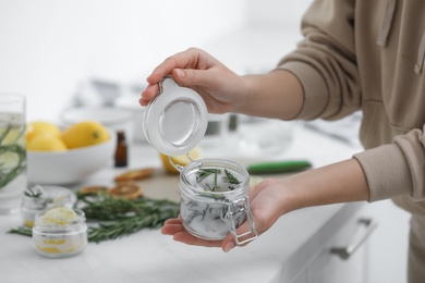 Photo of Woman making natural mosquito repellent candles at white table, closeup