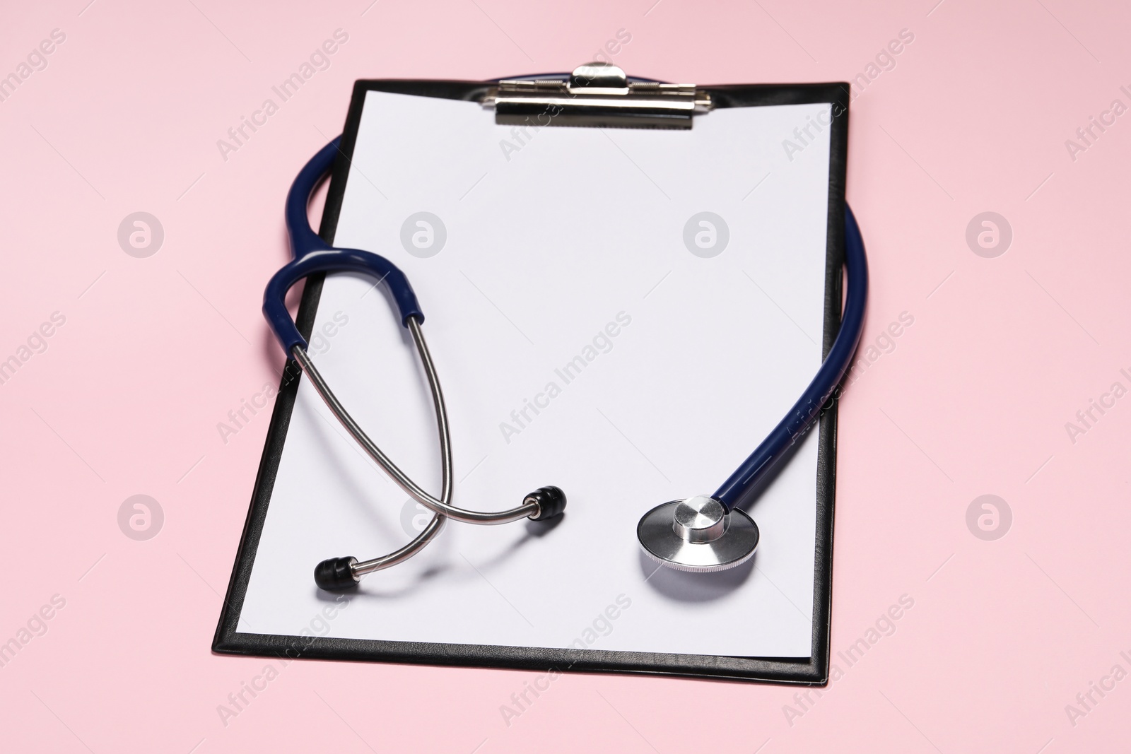 Photo of Stethoscope and clipboard on pink background. Medical tool