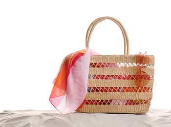 Stylish bag with beach accessories on sand against white background