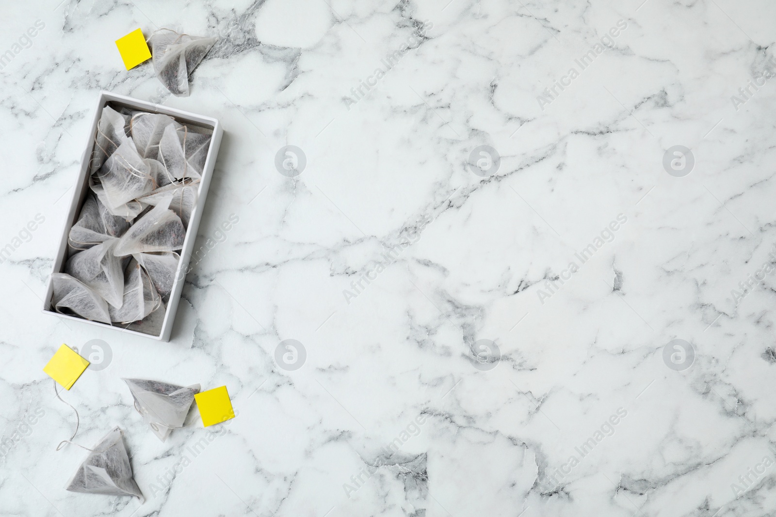 Photo of Box with tea bags and space for text on marble background, top view