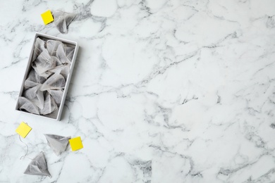 Photo of Box with tea bags and space for text on marble background, top view