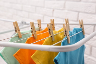 Photo of Different cute baby onesies hanging on clothes line near brick wall. Laundry day