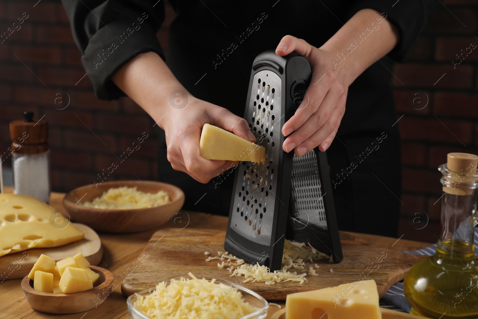 Photo of Woman grating cheese at wooden table, closeup