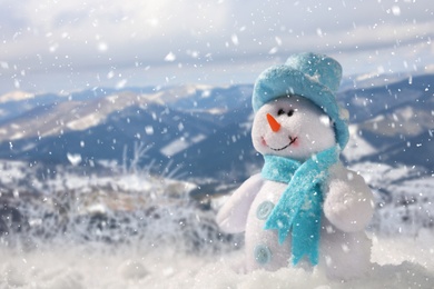 Image of Cute small decorative snowman outdoors on sunny day, space for text