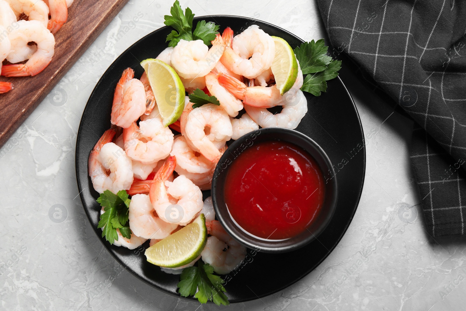 Photo of Tasty boiled shrimps with cocktail sauce, parsley and lime on light grey table, flat lay