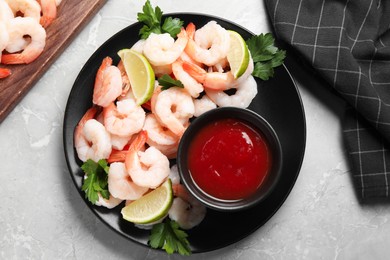 Photo of Tasty boiled shrimps with cocktail sauce, parsley and lime on light grey table, flat lay