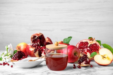 Photo of Honey, pomegranate and apples on white marble table. Rosh Hashana holiday