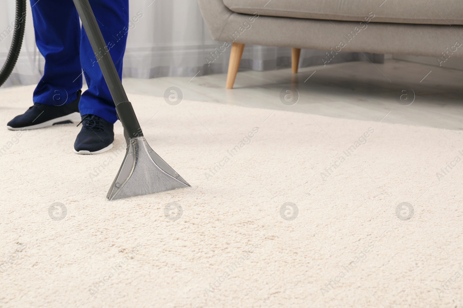 Photo of Man removing dirt from carpet with vacuum cleaner indoors, closeup. Space for text