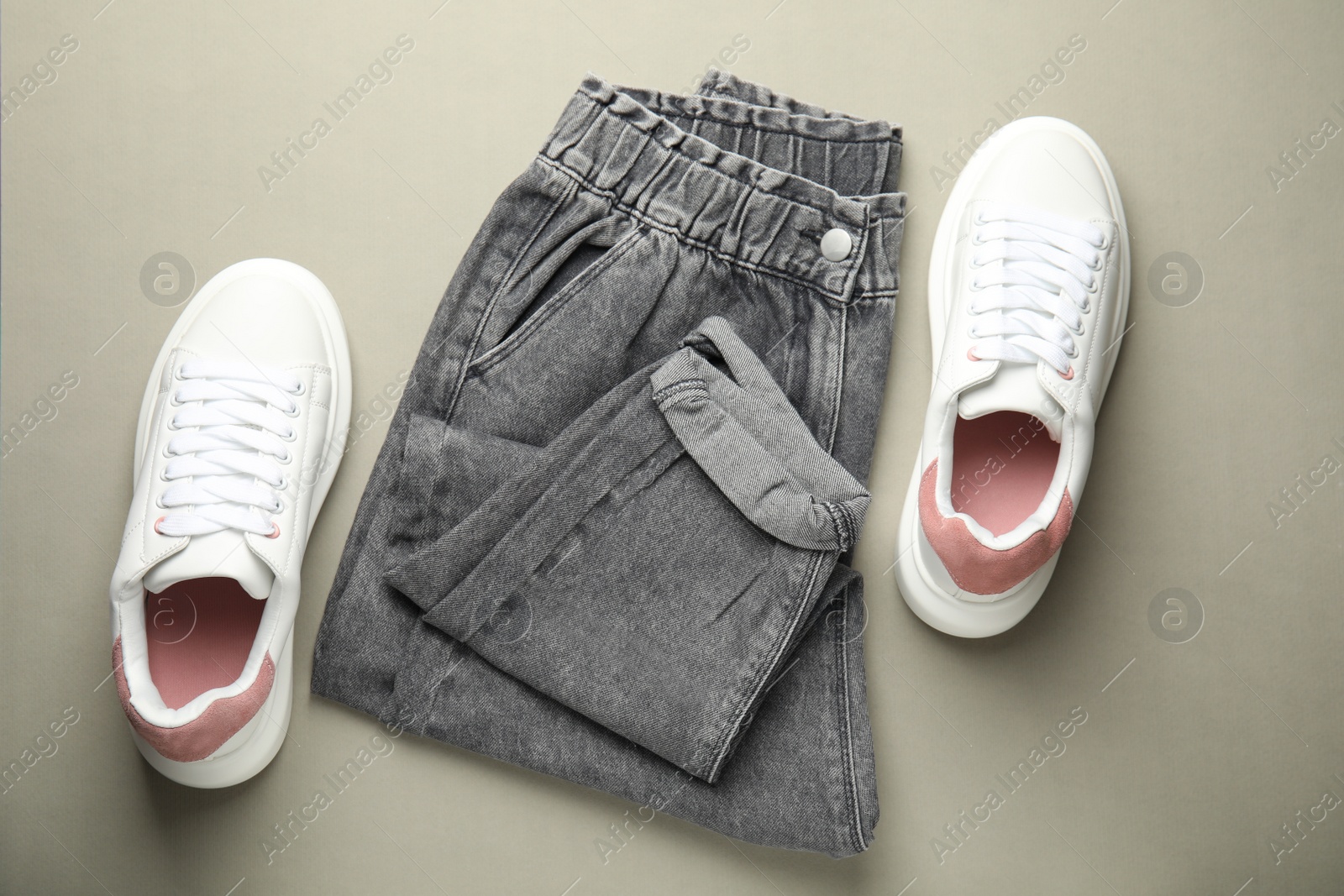 Photo of Stylish white sneakers and jeans on grey background, flat lay