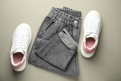 Photo of Stylish white sneakers and jeans on grey background, flat lay