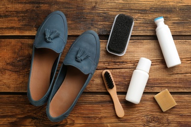 Stylish footwear with shoe care accessories on wooden table, flat lay