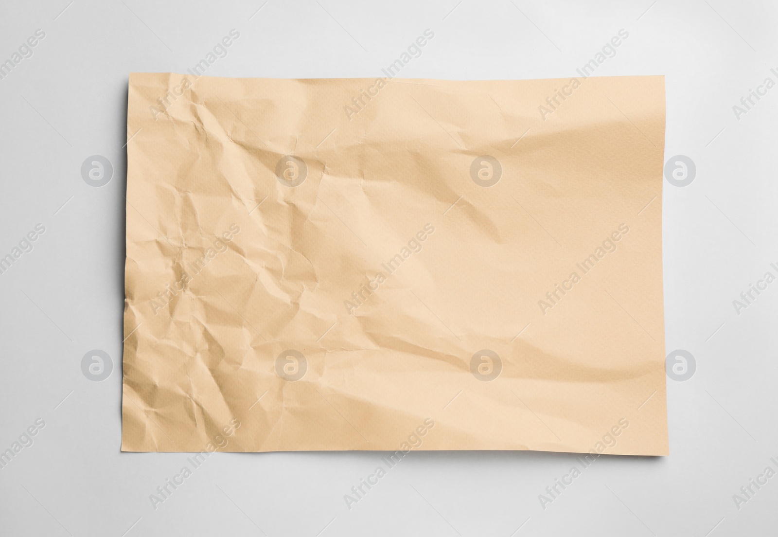 Photo of Sheet of crumpled brown paper on white background, top view