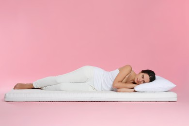 Photo of Young woman lying on soft mattress against pink background