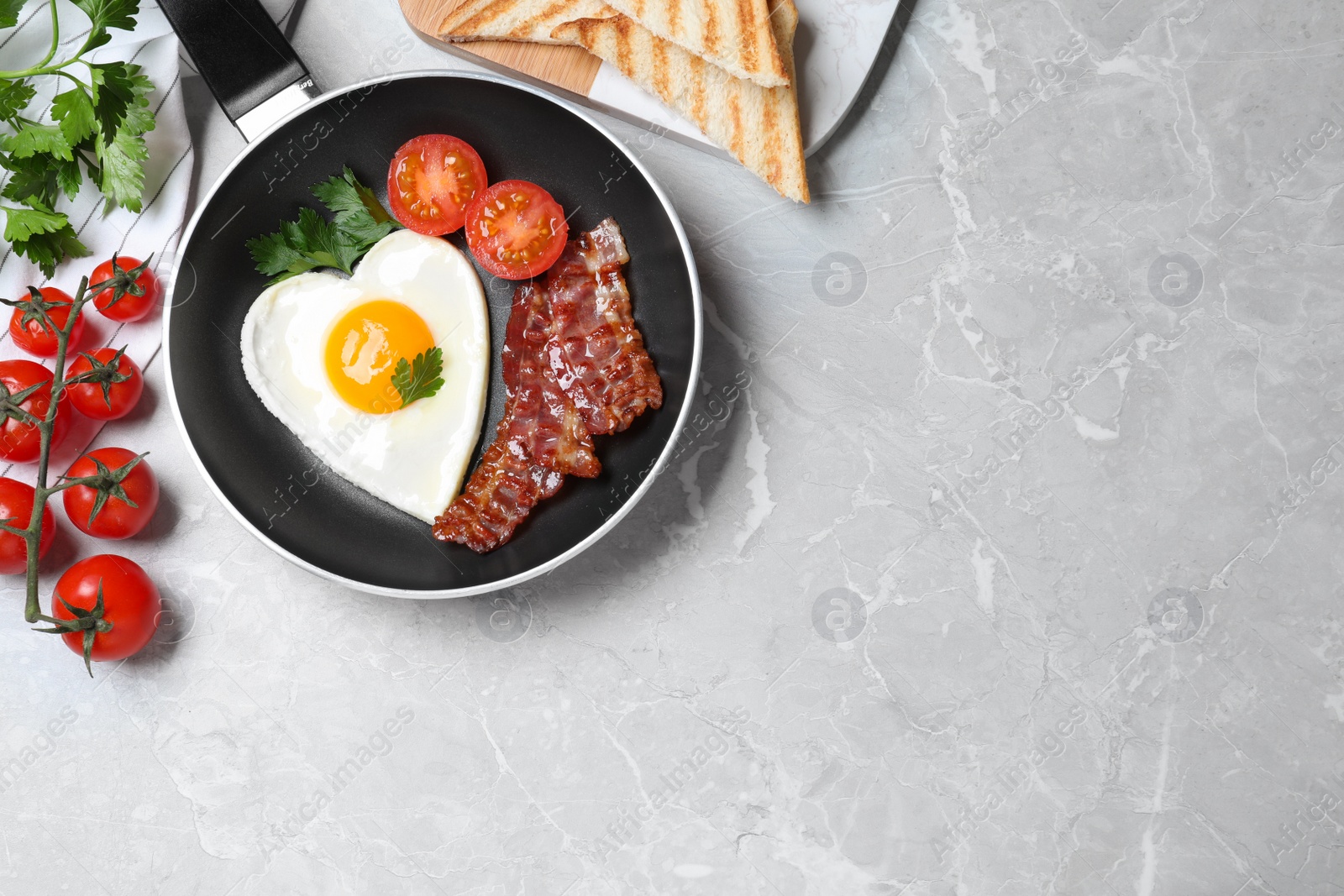 Photo of Tasty breakfast with heart shaped fried egg on grey table, flat lay. Space for text