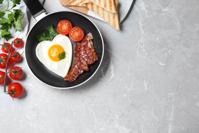 Tasty breakfast with heart shaped fried egg on grey table, flat lay. Space for text