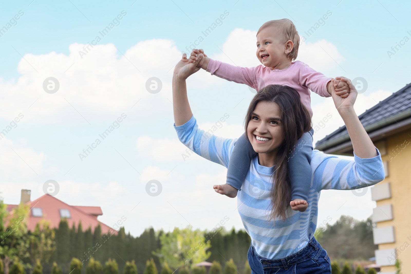 Photo of Happy mother playing with her cute baby at backyard on sunny day, space for text