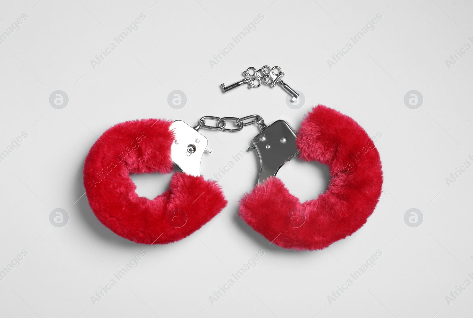 Photo of Red furry handcuffs and keys on white background, top view. Sex toy