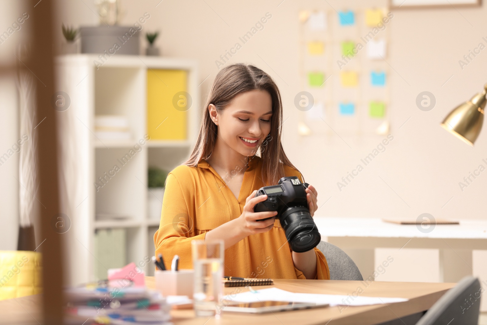 Photo of Young journalist with camera at table in office