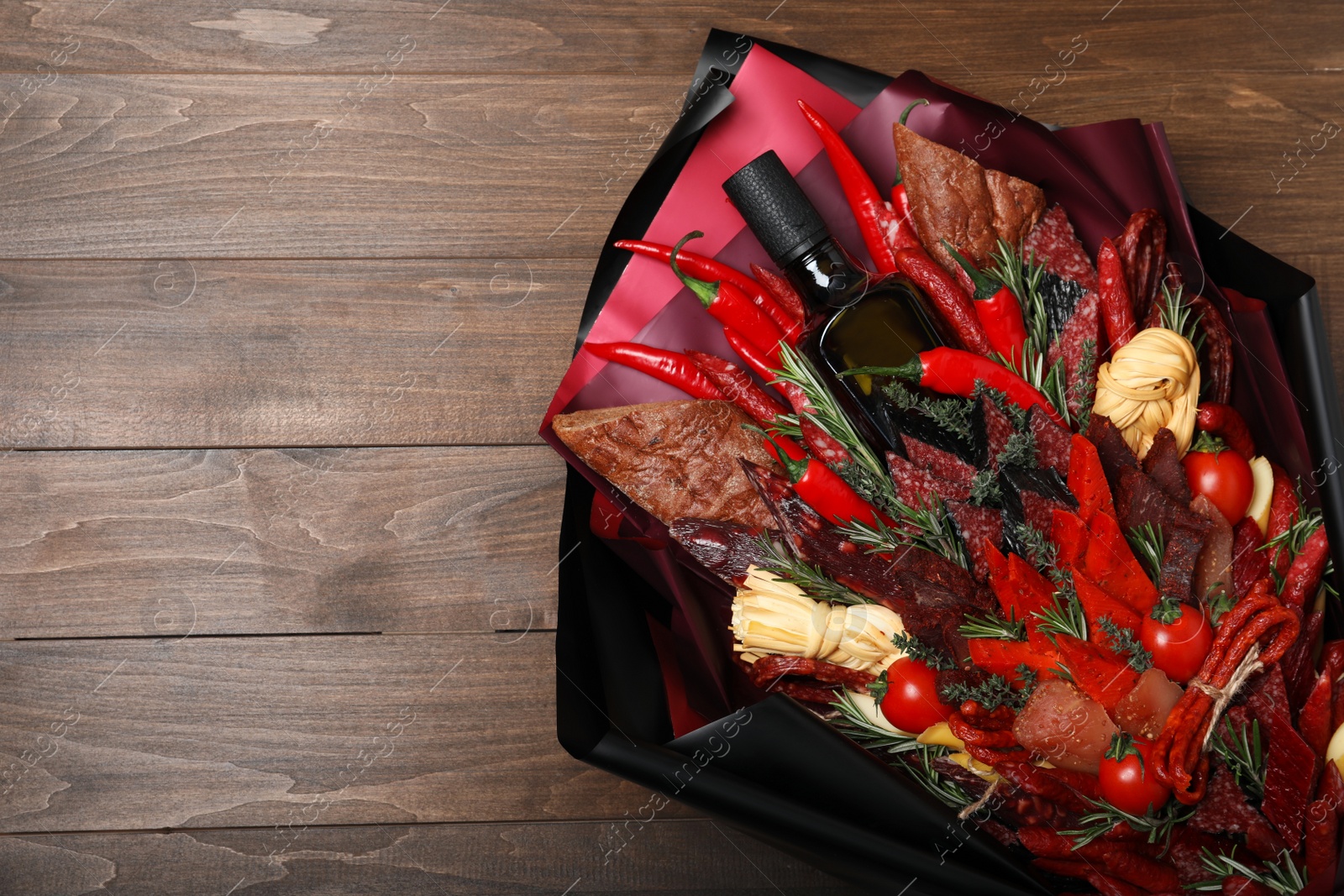 Photo of Beautiful edible bouquet with meat, cheese and vegetables on wooden table, top view. Space for text