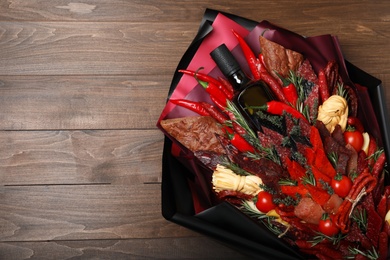 Beautiful edible bouquet with meat, cheese and vegetables on wooden table, top view. Space for text