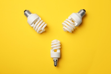 Photo of New fluorescent lamp bulbs on yellow background, top view