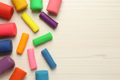 Different color play dough on wooden table, flat lay. Space for text