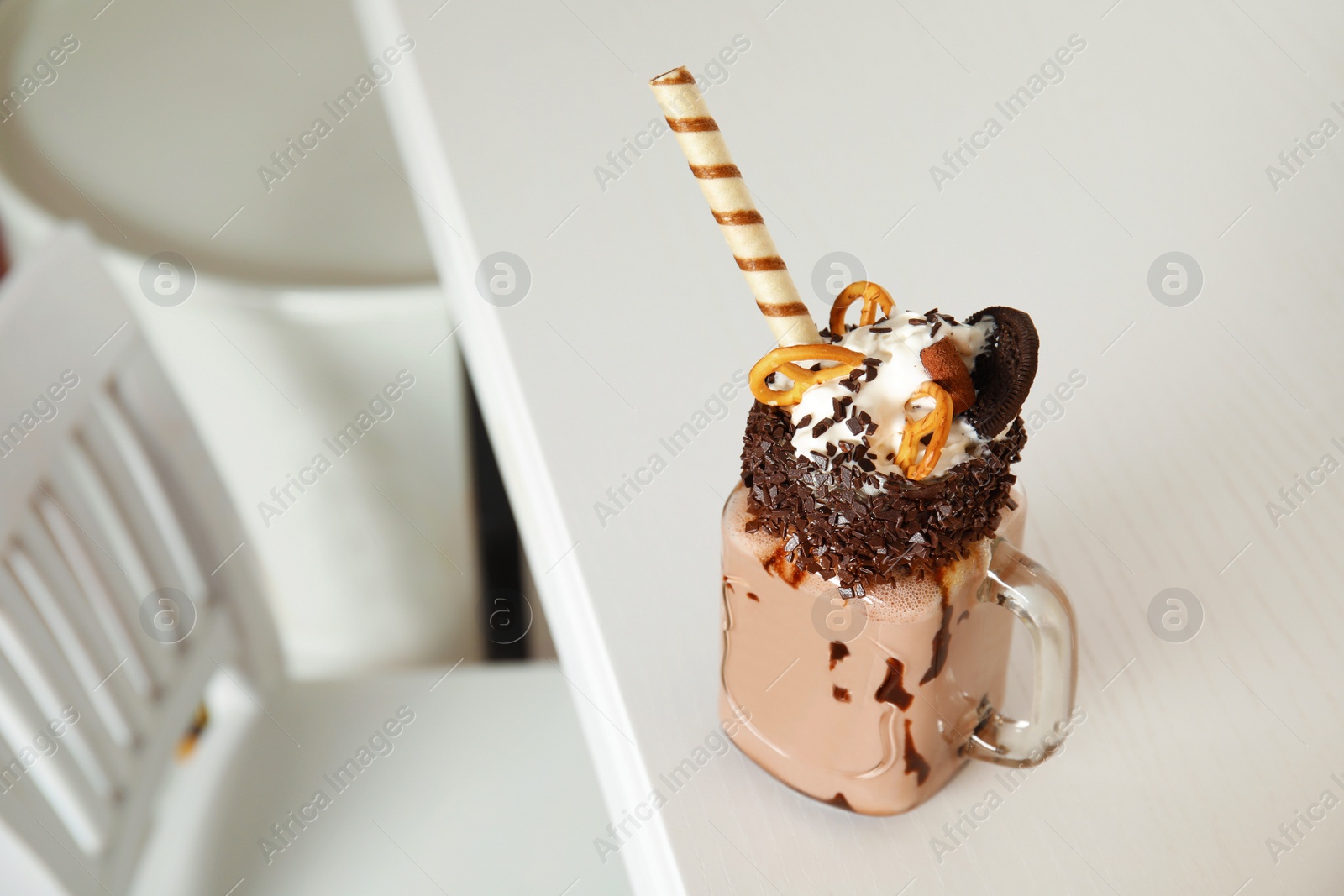 Photo of Tasty milk shake with sweets in mason jar on table at cafe. Space for text