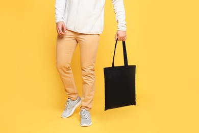 Young man with eco bag on yellow background, closeup