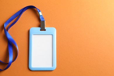 Photo of Blank badge with string on orange background, top view. Space for text