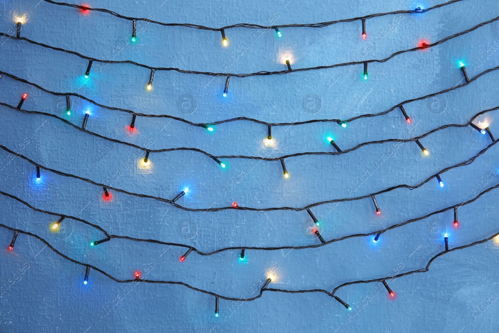 Photo of Beautiful bright Christmas lights on color background