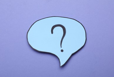 Photo of Paper speech bubble with question mark on violet background, top view