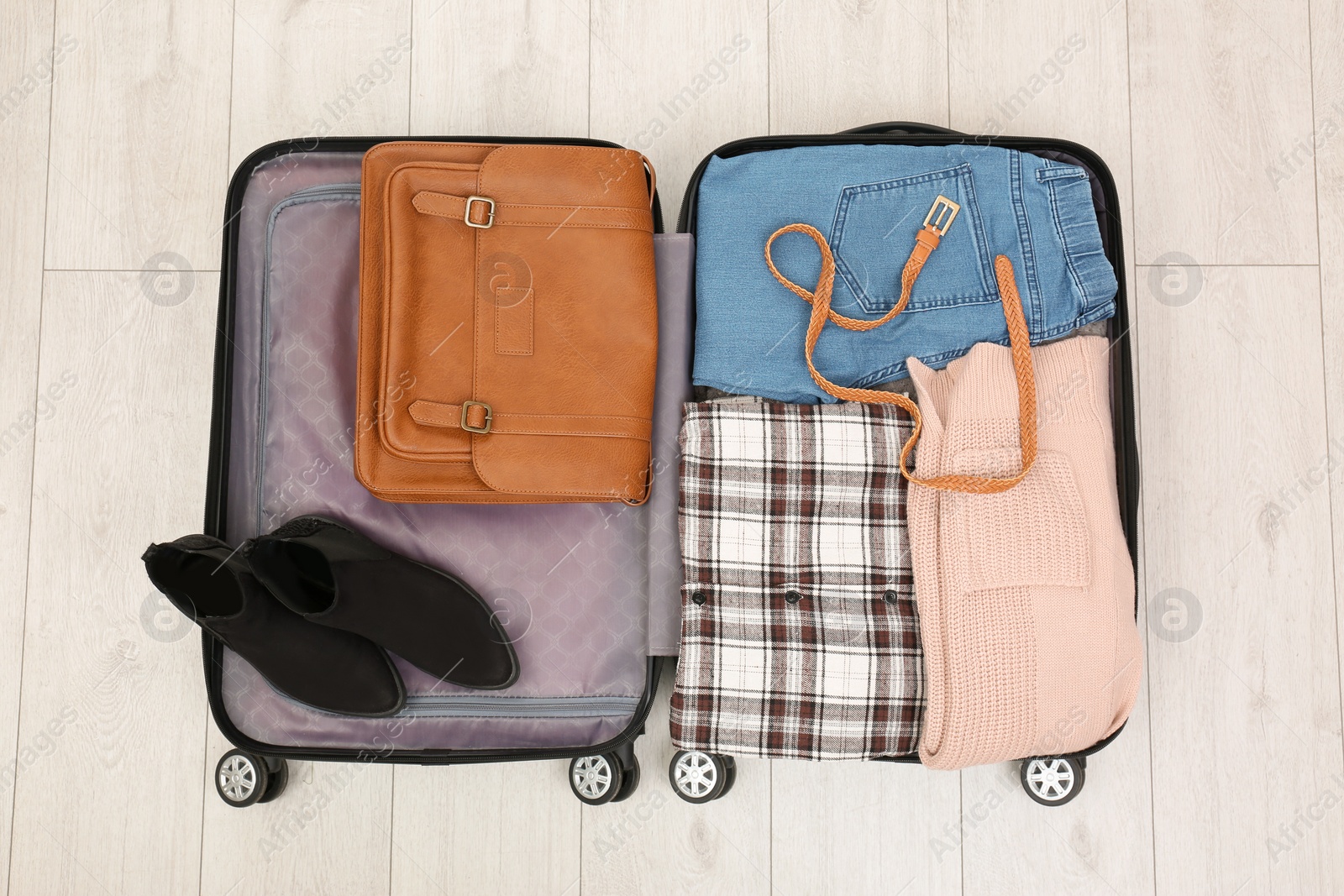 Photo of Packed suitcase with stuff on wooden background, top view