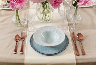 Stylish table setting with beautiful peonies and golden cutlery