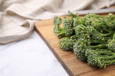 Photo of Fresh raw broccolini on white table, closeup and space for text. Healthy food