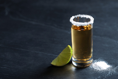 Photo of Mexican Tequila shot, lime slice and salt on grey table. Space for text