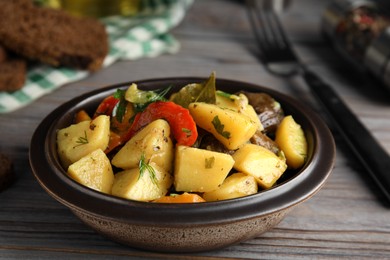 Photo of Tasty cooked dish with potatoes in earthenware served on wooden table