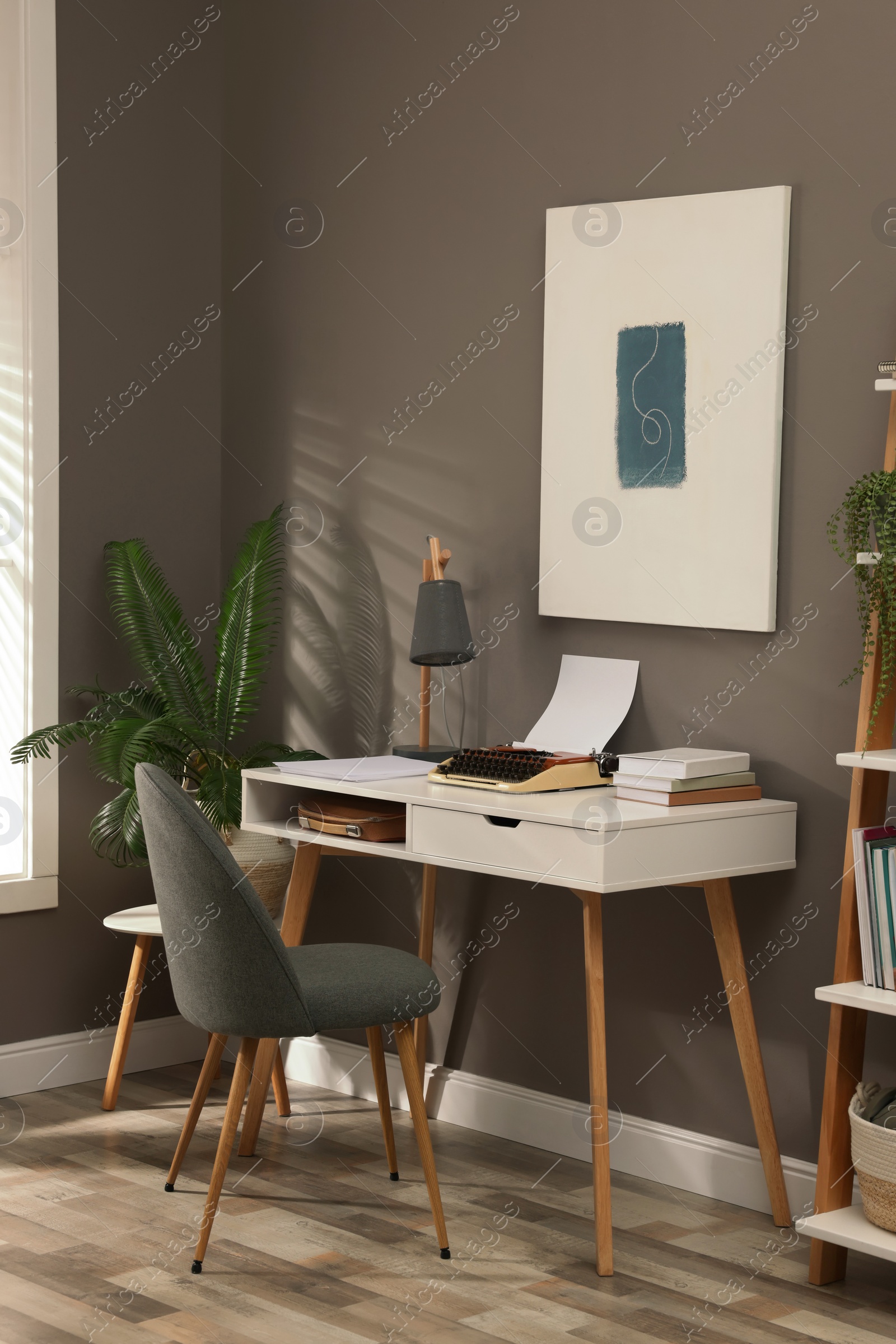 Photo of Comfortable writer's workplace interior with typewriter on desk near grey wall