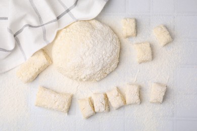 Photo of Making lazy dumplings. Raw dough and flour on white tiled table, flat lay