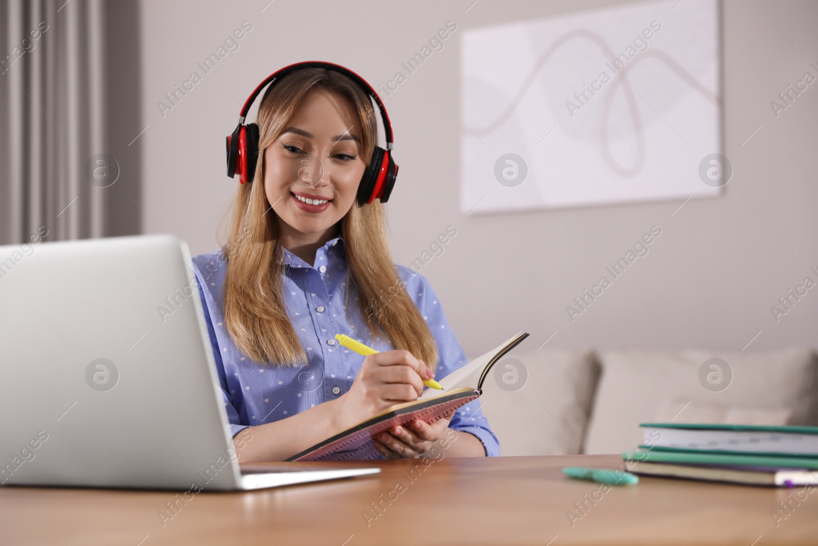 Photo of Young woman watching webinar at table in room